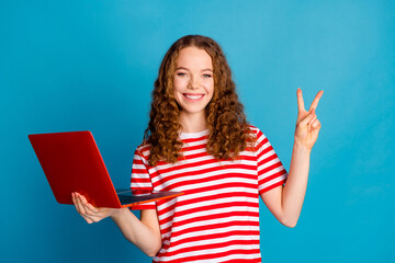 Sticker - Photo of good mood woman with wavy hairdo dressed striped t-shirt hold laptop show v-sign symbol isolated on blue color background