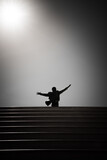 Fototapeta Tęcza - Silhouette of a man standing on the stairs and raising his hands. Statue of Domenico Modugno. Polignano a Mare, Italy