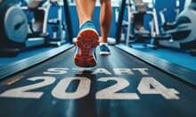 Close Up Of Feet Of Sportsman Runner Running On Treadmill With Word "START 2024" Written On Treadmill, In Fitness Club. New Year's Resolutions Theme.