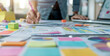 Selective focus with a person writing on a table with colorful sticky notes