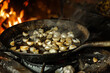 : A rustic kitchen scene where garlic cloves sizzle in a skillet, releasing their savory aroma as they caramelize to perfection.