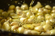 A close-up of garlic cloves bathed in golden olive oil, simmering gently in a skillet, infusing the air with their irresistible aroma.
