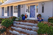 Front porch and stairs of house covered deeply in fall leaves, home maintenance leaf clean up, horizontal aspect