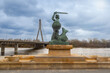 A statue of a mermaid with a sword against the background of a bridge. Warsaw.
