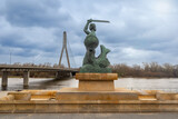 Fototapeta  - A statue of a mermaid with a sword against the background of a bridge. Warsaw.