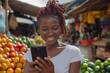 Smiling young African woman using smartphone in local market, technology and daily life concept