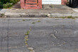 Deteriorating street surface, curb and sidewalk, crumbling infrastructure, transportation copy space, horizontal aspect