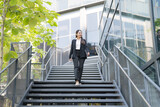 Fototapeta Natura - Confident businesswoman descending outdoor stairs
