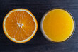 Half an orange and a glass of freshly squeezed orange juice on a wooden background, closeup, top view
