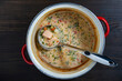 Leftovers cream fish soup in a saucepan with a ladle on a wooden table, closeup, top view