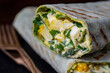 Homemade burrito wraps with boiled eggs, potato, green wild garlic and sour cream for healthy breakfast , closeup