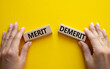 Merit or Demerit symbol. Concept word Merit or Demerit on wooden blocks. Businessman hand. Beautiful yellow background. Business and Merit or Demerit concept. Copy space