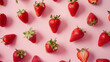 Strawberries laid out on a bright light pink background