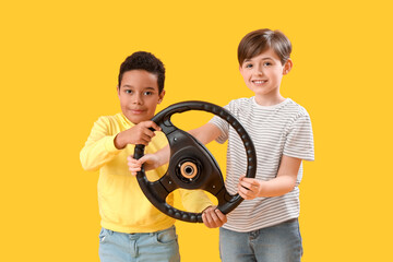 Wall Mural - Little boys with steering wheel on yellow background. Children's Day celebration