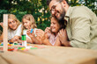 © Zamrznuti tonovi - Father is hugging a girl sitting at picnic table with family in nature