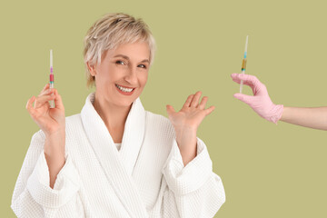 Wall Mural - Mature woman and cosmetologist with injections on green background