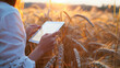 Female Farmer Using Tablet in Wheat Field at Sunset