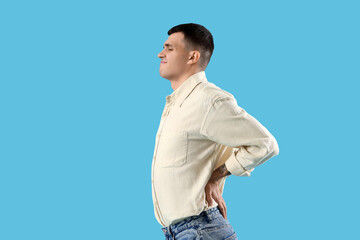 Canvas Print - Young man suffering from back pain on blue background