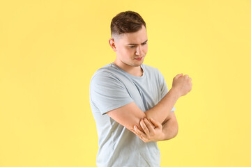 Canvas Print - Young man suffering from arm pain on color background