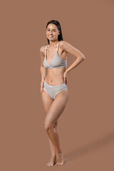 Wall Mural - Slim young woman in cotton underwear on brown background