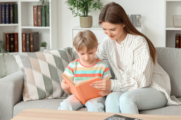 Sticker - Little boy with his mother reading book on sofa at home