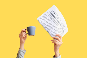 Sticker - Female hands with newspaper and cup of coffee on yellow background