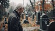 Elderly Man Reflecting in Cemetery - Side profile of a pensive elderly man visiting a graveyard on a grey, foggy day.