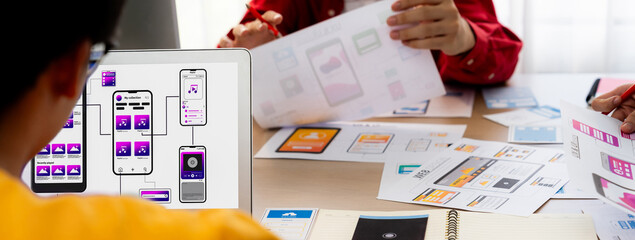 Panorama banner of startup UX developer or company employee design user interface or UI prototype for mobile application or website software with software display on laptop monitor in office. Synergic