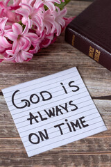 Wall Mural - God is always on time, inspirational handwritten quote with holy bible and flowers on wood. Christian biblical concept of patience, waiting on Jesus Christ, answered prayer, and faith.