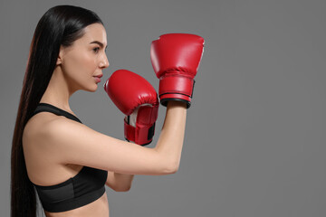 Poster - Beautiful woman in boxing gloves training on grey background. Space for text