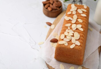 Cake with fresh almond flakes and nuts on white textured table, closeup. Space for text