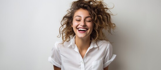 Poster - Woman with curly hair wearing a white shirt looking joyful and happy against a plain white backdrop