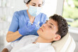 © JackF - Cosmetologist in medical scrubs, cap and gloves giving filler injection to young man