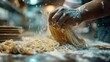 A detailed close-up captures the hands of a chef dusted with flour as they skillfully shape fresh, golden pasta dough into thick noodles.
