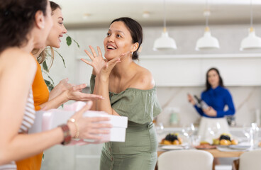 Wall Mural - Girlfriends greet each other and give gift when meeting in kitchen..