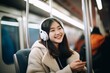© Surachetsh - Smiling young person listening to music song singer rock band in headphones earphones, choosing sound track on cellphone isolated in Train Subway tube background.