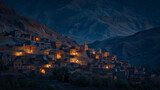 Fototapeta  - At the foot of a towering mountain range a hidden village lies nestled in the shadows. The warm glow of moonlight reveals the intricate . .