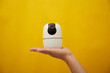 © Cuong - A hand hold a wireless security camera on yellow background