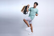 Full length photo of young Asian guy holding shopping bags and celebrate discount sale offer isolated on white background 