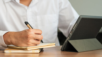 Wall Mural - businessman working at work table,home office desk background, checklist writing planning investigate enthusiastic concept. Male hand taking notes on the notepad.	
