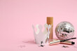© Pixel-Shot - Paper crown with makeup cosmetic products and disco ball on pink background. Prom concept