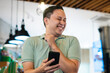 © Hardollin - Adult Man Laughing at Smartphone Content in a Relaxed Setting at Cafe