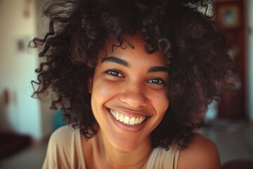 A woman with curly hair is smiling and looking at the camera