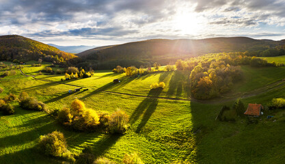 Poster - Aerial view in summer in Slovakia. Ggreen meadows and fields, grass and trees, rural road at dawn in spring. Top drone view of mountain countryside
