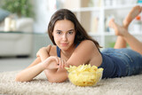 Fototapeta Tematy - Beautiful woman looks at you eating potato chips