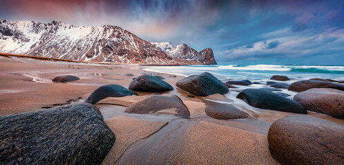 Wall Mural - big boulders on the coast of norwegian sea. panoramic spring view of unstad beach. great sunrise onl