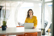 © Westend61 - Confident creative businesswoman with laptop at table in office