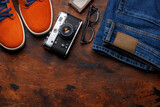 Fototapeta  - Men's Clothing on wooden Background: Jeans, Sneakers, Eyeglasses