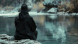 Man in black hooded hat sitting on a rock and looking