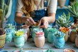 A person crafting colorful potted succulents in a pottery workshop with various plants and tools